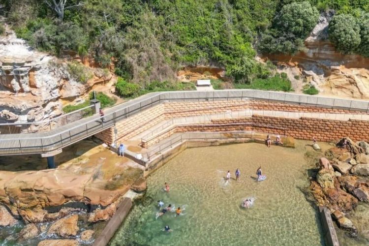 An aerial view of a mandmade rockpool with a boardwalk behind it